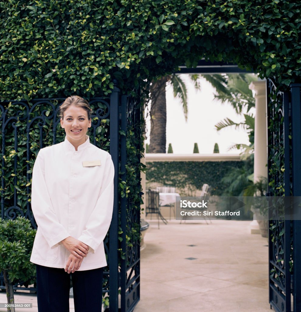 Hotel attendant standing by gate, portrait  Hotel Stock Photo