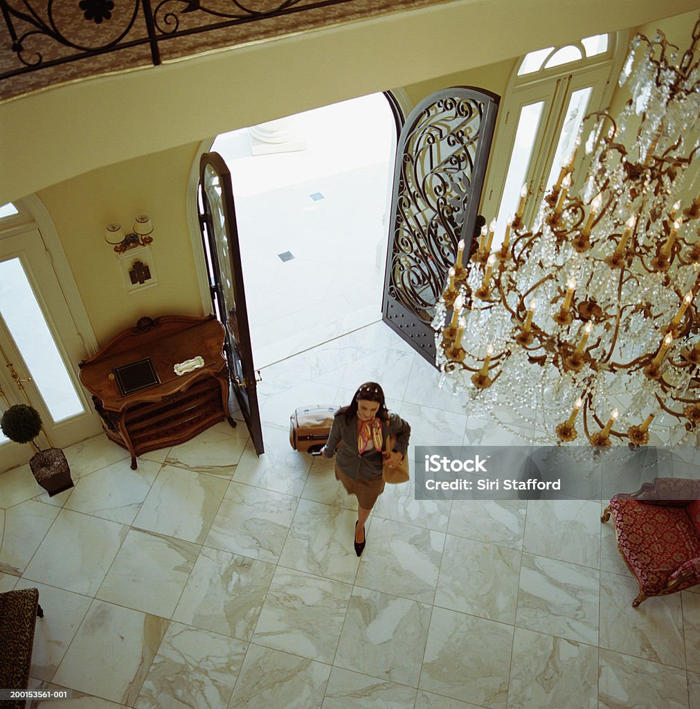 Woman with luggage, walking into hotel, elevated view  Hotel Stock Photo