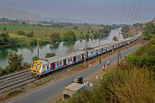 Kamshet, Maharashtra, India-February 21st, 2023: Pune to Lonavala local EMU train with Siemens rake is speeding parallel to river Indrayani.