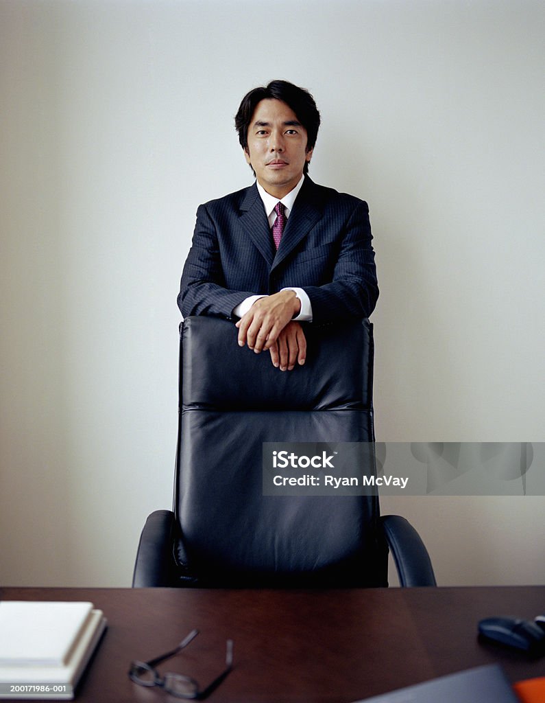 Mature businessman standing behind chair in office, portrait  Businessman Stock Photo