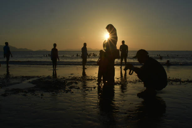 Silhouette The people of the coastal city of Banda Aceh enjoy the beauty of the Javanese village beach at sunset. Banda Aceh-Indonesia. 07/23/2017 18:17:30 +0000