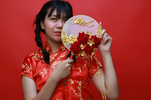 Portrait A Young Asian girl dressed in traditional cheongsam called qipao with a  beautiful handmade fan on Chinese New Year's Day