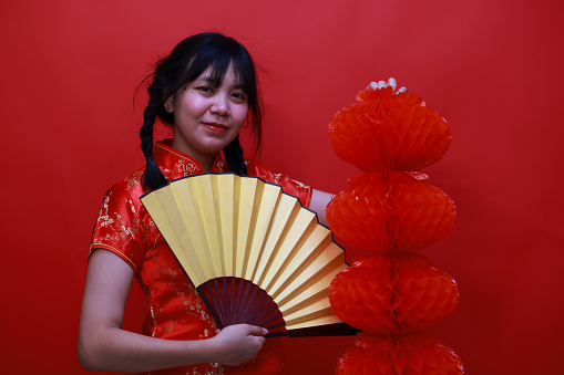 A cheering girl with a red Chinese lantern and Yellow hand fan   in the studio Chinese New Year Festival concept