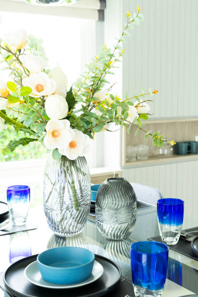 istock White flowers in vase on modern dinning table with blue plates. 2001810925