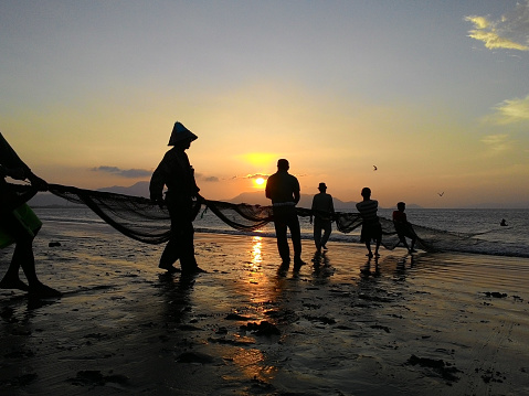 Banda Aceh 04/06/2014\nfishermen clean their fishing nets as the sun sets and shines red in the kampung jawa of Banda Aceh
