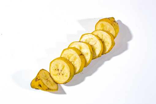 one banana that has been cut into many parts, and served on a plain white background