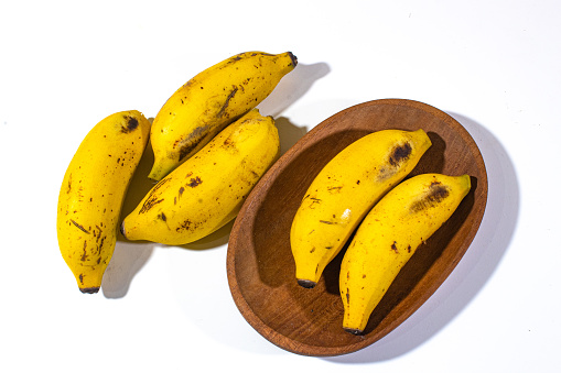 three bananas on a plain white background and two bananas on a wooden plate three bananas on a plain white background and two bananas on a wooden plate