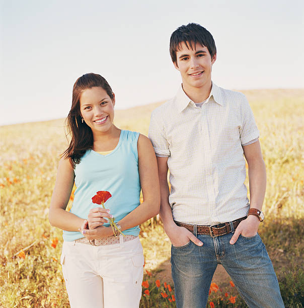 pareja joven en el campo, mujer agarrando poppy (eschscholtzia califo - poppy oriental poppy plant spring fotografías e imágenes de stock