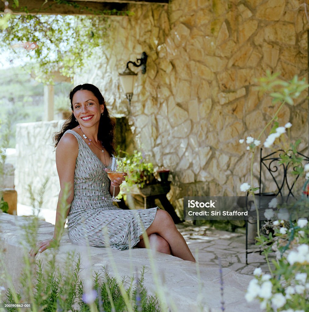 Frau sitzt auf Stein Wand und hältst Wein Glas - Lizenzfrei 35-39 Jahre Stock-Foto