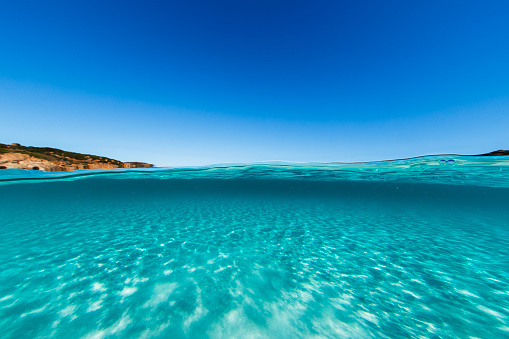 Split shot of crystal clear turquoise blue water with white sand on a clear sunny day. Photographed in Cape LeGrand, Western Australia.