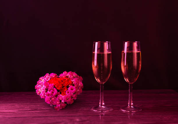 dos copas de champán rosado y un gran corazón hecho de flores frescas naturales. día de san valentín. hermosa foto. - champagne rose flower pink fotografías e imágenes de stock