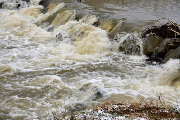 City river milky view between protective walls with a small waterfall