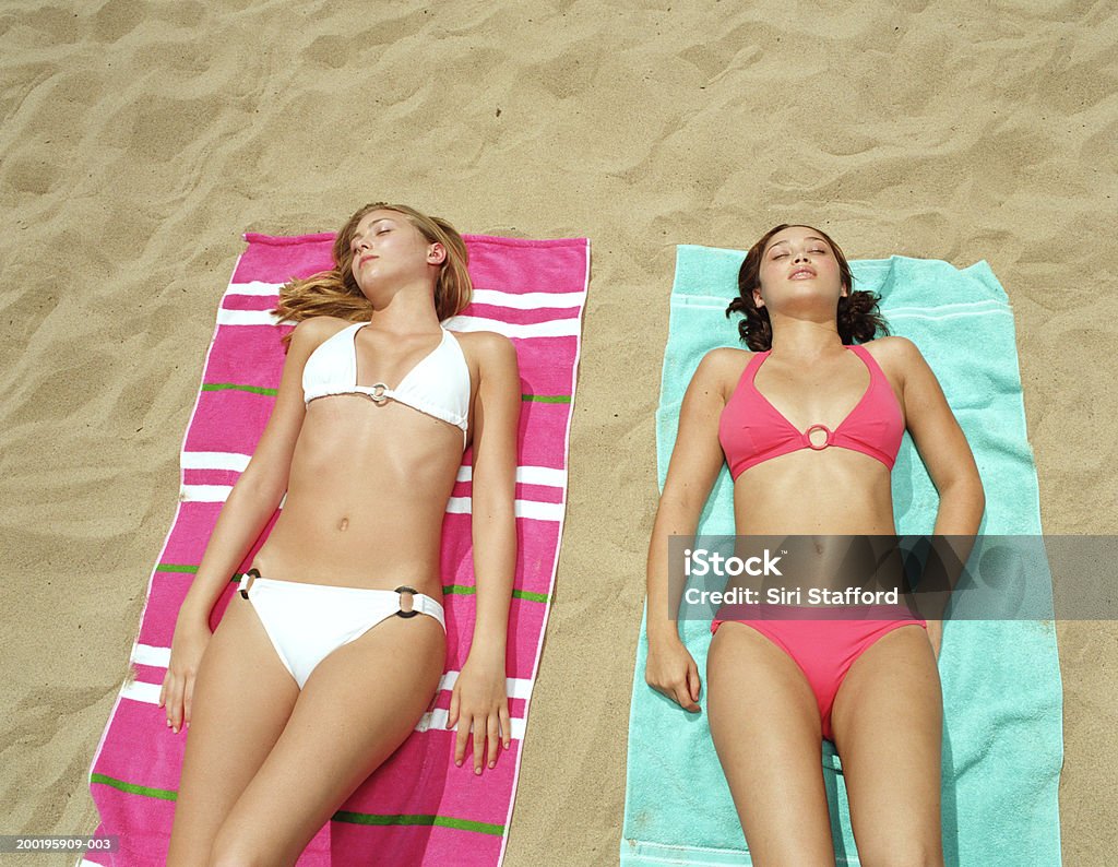 Mujeres jóvenes en bikinis, acostado de toallas en la playa, - Foto de stock de Biquini libre de derechos