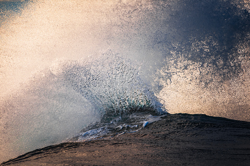 Close up of exploding wave breaking on reef in the ocean with warm morning light. Shot off the south west coast of Australia.
