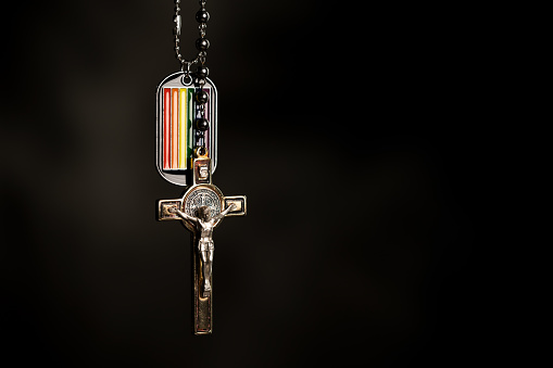 Crucifix and LGBT necklace on dark background