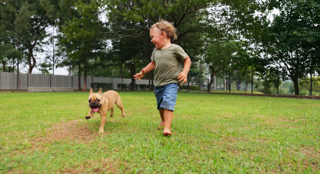 Toddler, barefoot and carefree, runs by grass, joined by adorable puppy, slow-mo