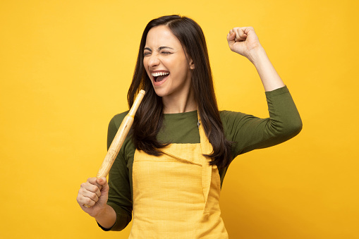 Photo of pretty positive young woman in yellow apron isolated on yellow background