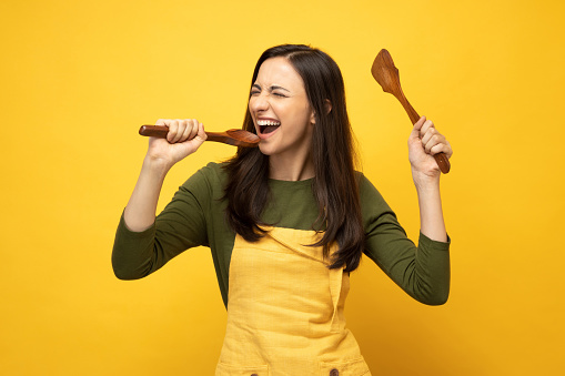 Photo of pretty positive young woman in yellow apron isolated on yellow background