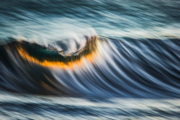 istock Slow shutter blur of smooth wave breaking on reef in the ocean with ambient golden light 2002000766