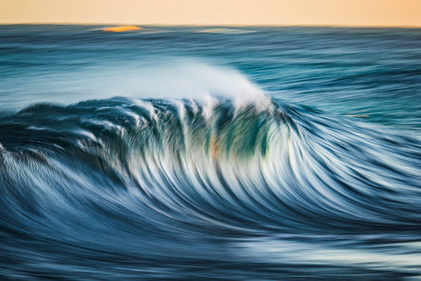 istock Slow shutter blur of smooth wave breaking on reef in the ocean with ambient golden light 2002001783