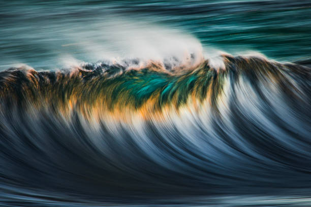 Abstract painting of powerful sea waves rolling and splashing over water surface against orange sky at sunset