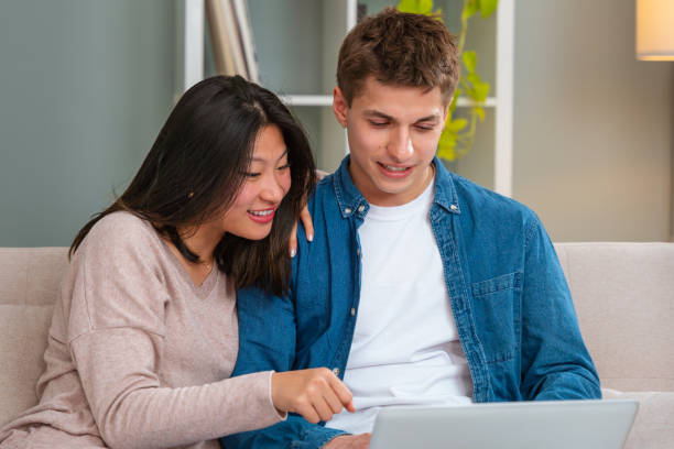 istock Happy multiethnic man and woman have fun browsing internet on laptop. Technology concept. 2002017475