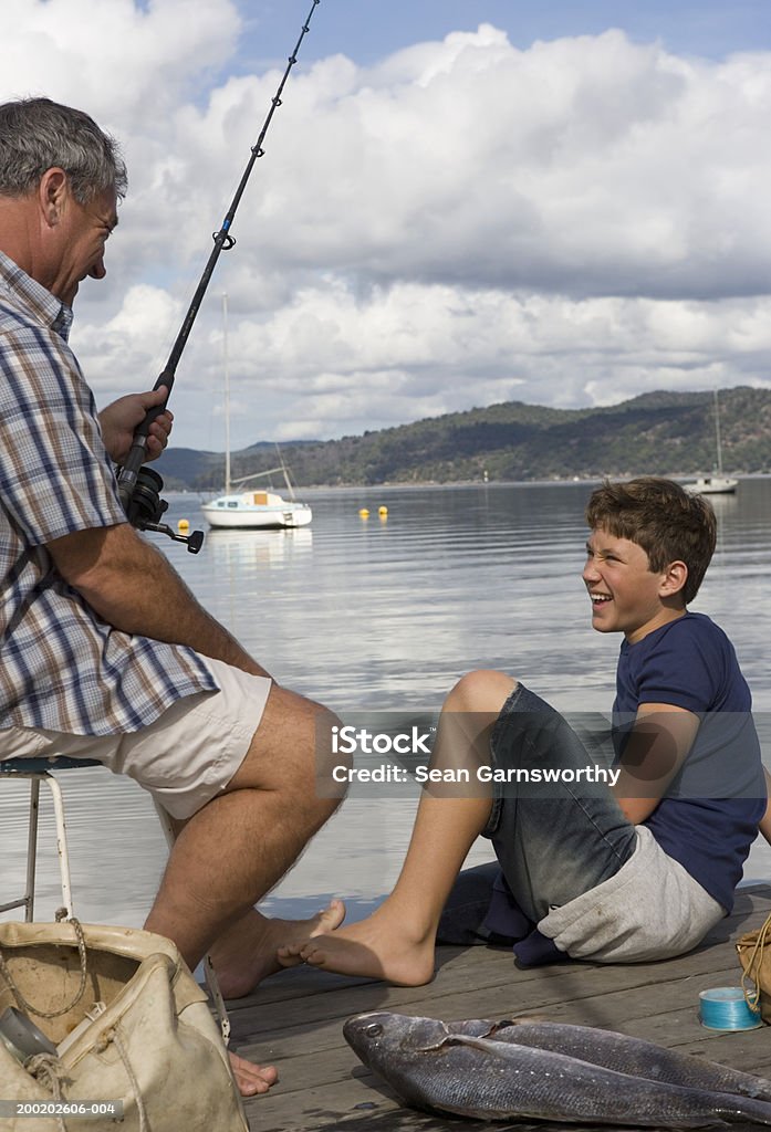 Ojciec i syn (12-14) sieć z nabrzeży, syn patrzy - Zbiór zdjęć royalty-free (Ojciec)
