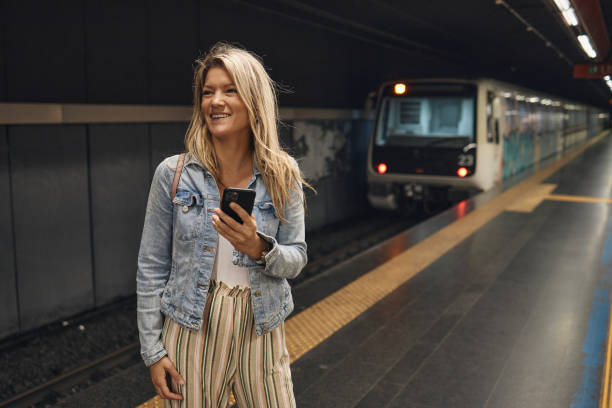 istock Young female tourist using a phone while waiting for a train 2002056532