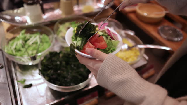 Woman picking up vegetables for lunch salad