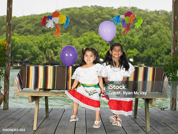 Photo libre de droit de Deux Soeurs Assis À Table De Piquenique Tenant Des Ballons Por banque d'images et plus d'images libres de droit de 4-5 ans