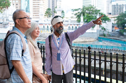 Two senior Asian traveler exploring the heritage and cultural tour with local tour guide in the city of Kuala Lumpur. Active & Healthy Lifestyles, Senior & Retirement, Financial Freedom Concepts.