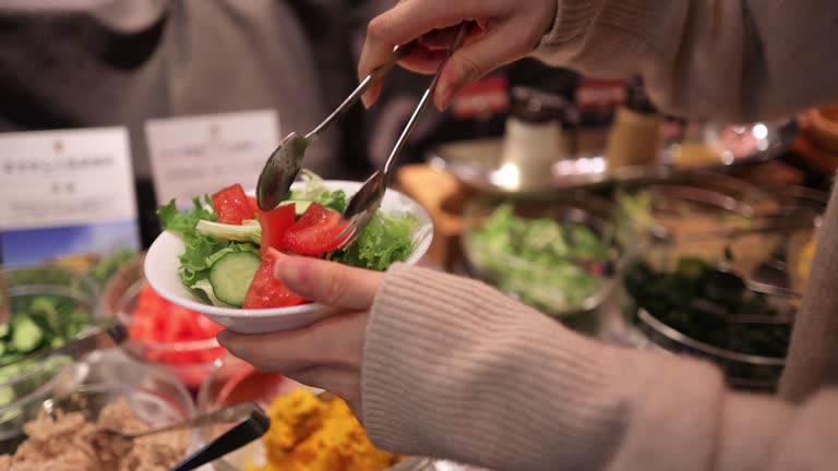 Woman picking up vegetables for lunch salad