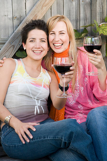 Two women holding wine glasses in garden, smiling, portrait stock photo