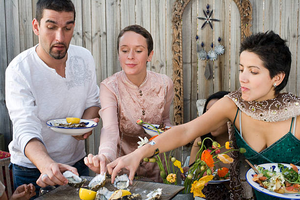 Group of people dining in garden, taking oysters from plate stock photo