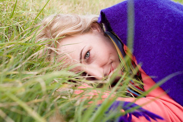 Woman lying on grass, under blanket, smiling, portrait, close-up stock photo