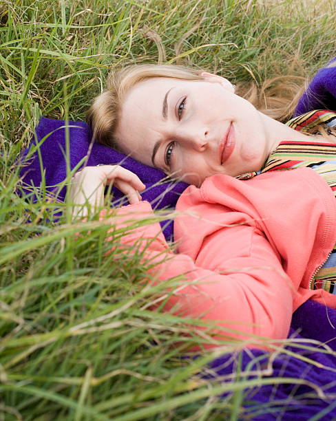 Woman lying on blanket on grass, smiling, portrait, close-up stock photo