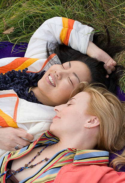 Two women lying on blanket on grass, eyes closed, close-up stock photo