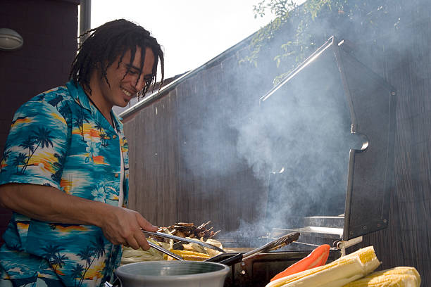 Young man tending barbecue in garden, smiling stock photo