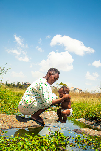 A young  african  mother with her baby  by the pond