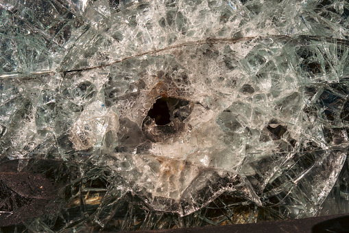 Bullet hole in armor-piercing glass. Armor piercing glass of damaged military infantry fighting vehicle during war between russia and Ukraine. Background and texture bulletproof glass after an attack