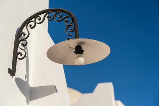 Street lamp with a light bulb on a white wall on a sunny clear day on the street in the resort town of Sharm El Sheikh, Egypt, close up