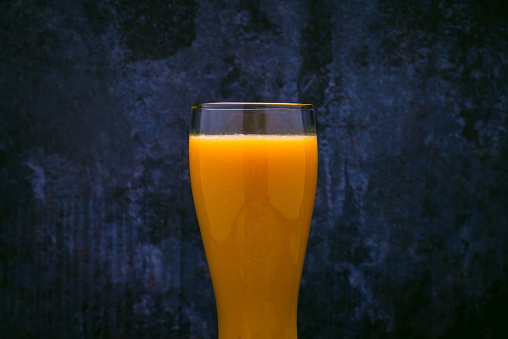 Glass with mango juice. Blue background.