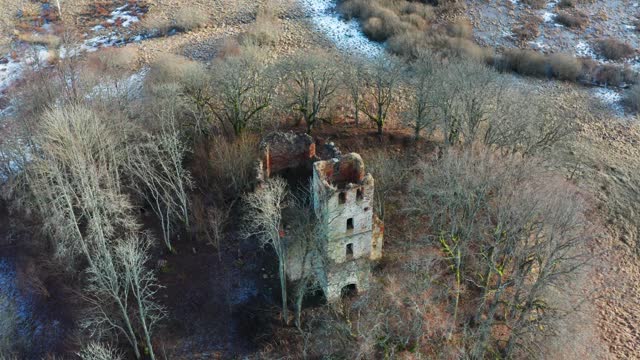 Aerial view of old church bell tower and wall remains among bare trees