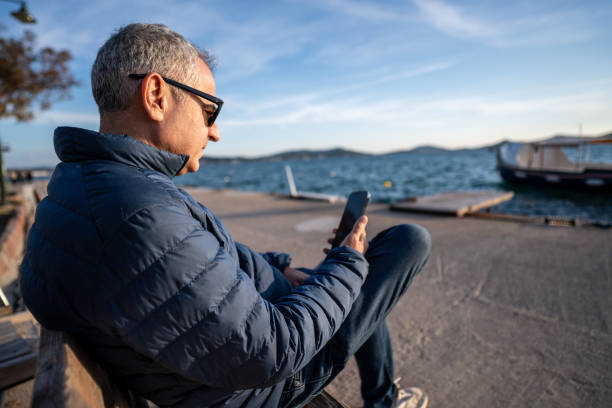 istock senior man is looking smartphone at shore horizontal communication still 2002132956