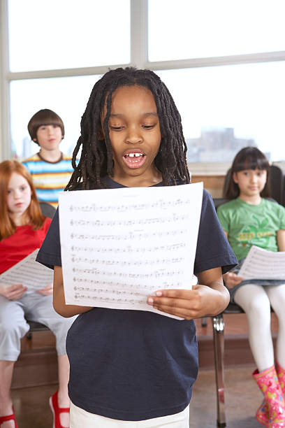 aluna (de 6 a 12) cantando de música de folha em sala de aula - sheet music music classroom education - fotografias e filmes do acervo