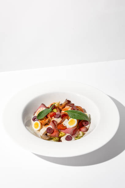 Roast beef salad with quail eggs and vegetables artistically arranged on a white plate