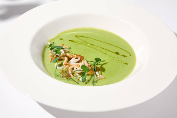 istock Spinach Cream Soup with Calamari Topping, Artfully Presented on a White Plate with Shadow, Perfect for Gourmet Food Advertising 2002139515
