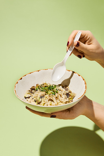 Elegant Hand Eating Mushroom Risotto with Truffle Oil, Healthy Concept. Ideal for Culinary Blogs and Gourmet Presentations.