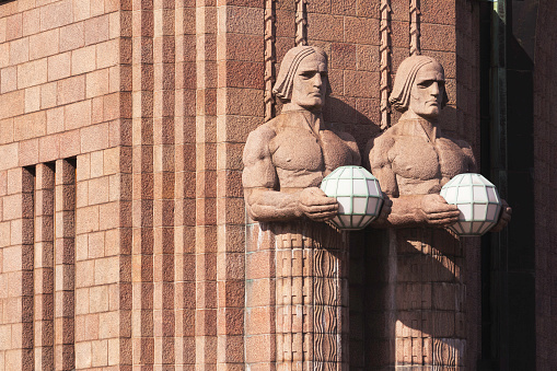 Closeup of two (of four) stone sculptures, known as Lyhdynkantajat, outside the main entrance of the Helsinki railway station. The sculptures were completed in 1914 and designed by Emil Wikström (1864-1942).