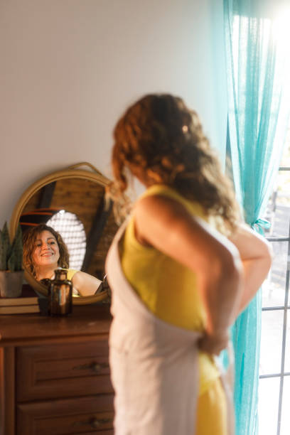 istock Woman looking in the mirror while tying her apron 2002218953